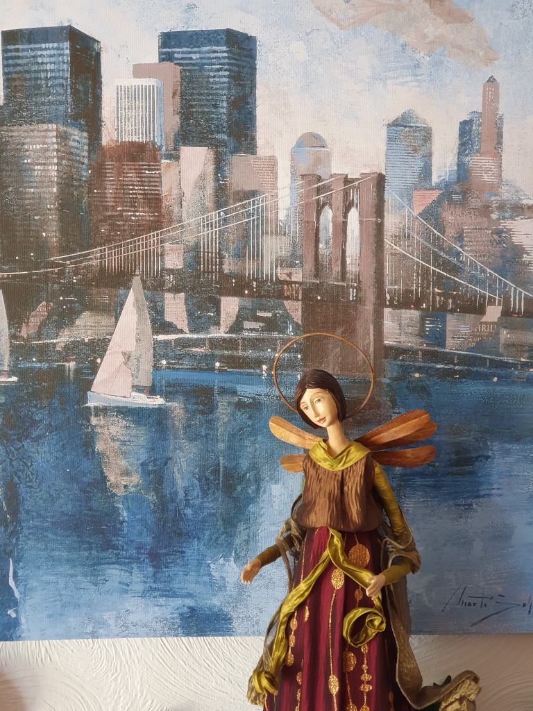 Picture of the Brooklyn Bridge on our wall; large porcelain-faced angel in front